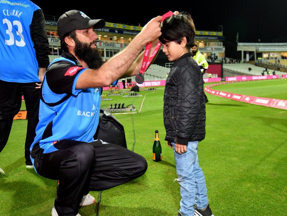 Moeen Ali lifts the trophy and gives his medal to a child. 